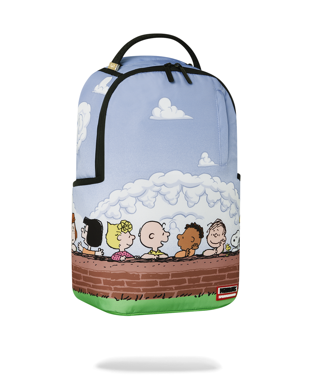 Sprayground Peanuts Fam Deluxe Backpack in use, connected to carry-on luggage