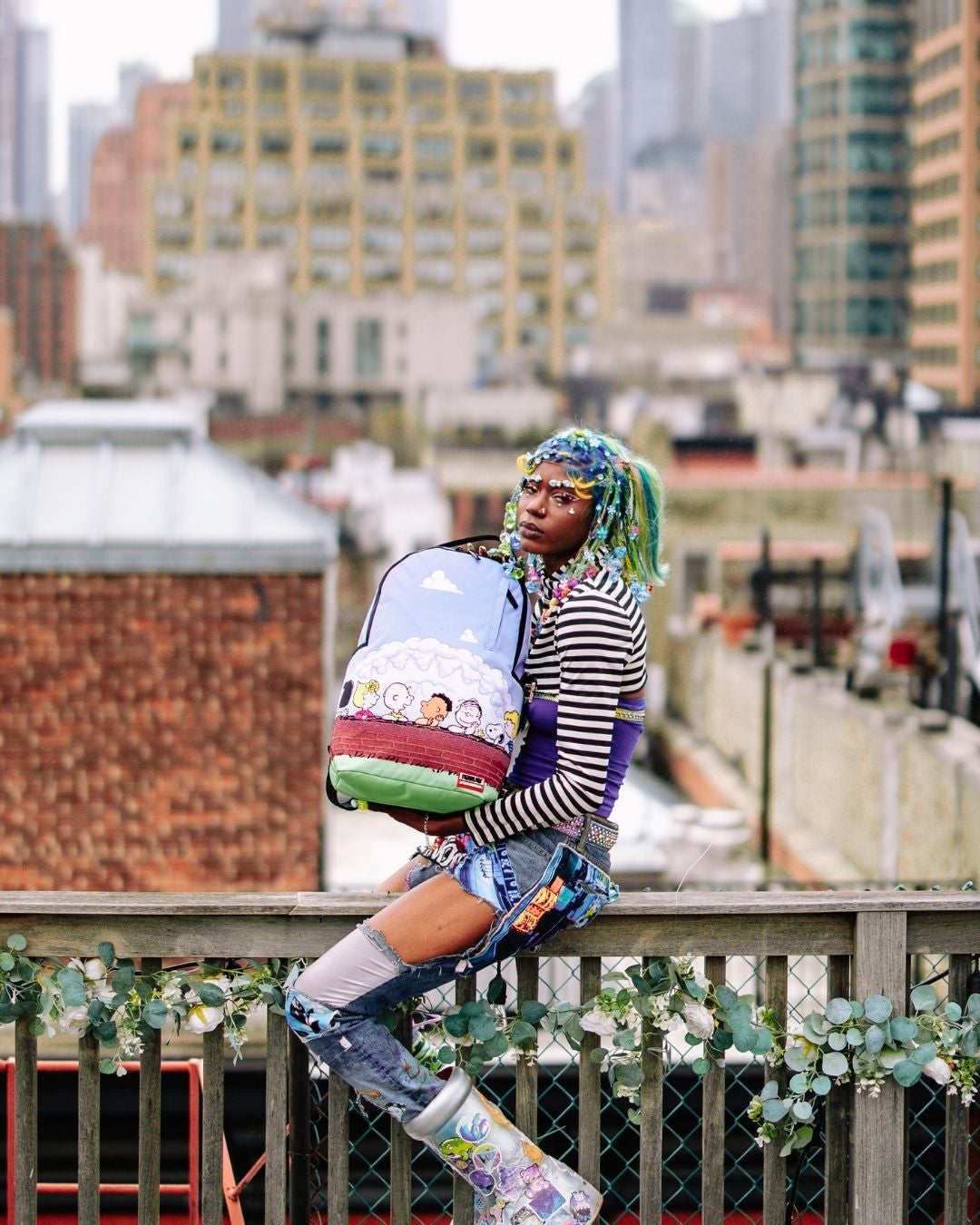 Sprayground Peanuts Fam Deluxe Backpack in use, connected to carry-on luggage