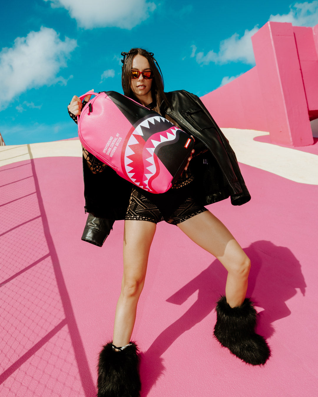 Woman carrying the pink Sprayground backpack in a busy airport terminal