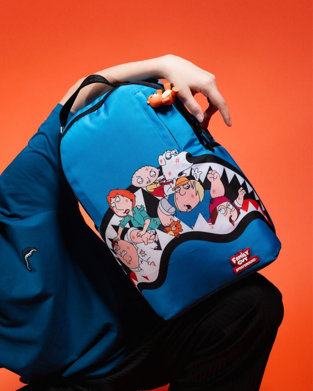 A clear Sprayground Backpack with Family Guy design, showcasing its multiple pockets and ergonomic mesh back padding.