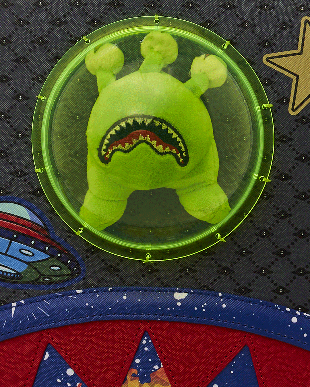 Front angle of the designer backpack showing plush alien bubble and gold hardware