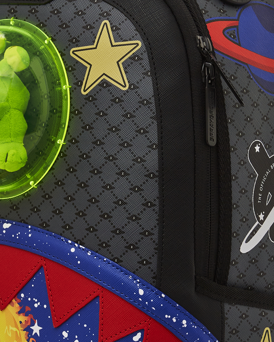 Front angle of the designer backpack showing plush alien bubble and gold hardware