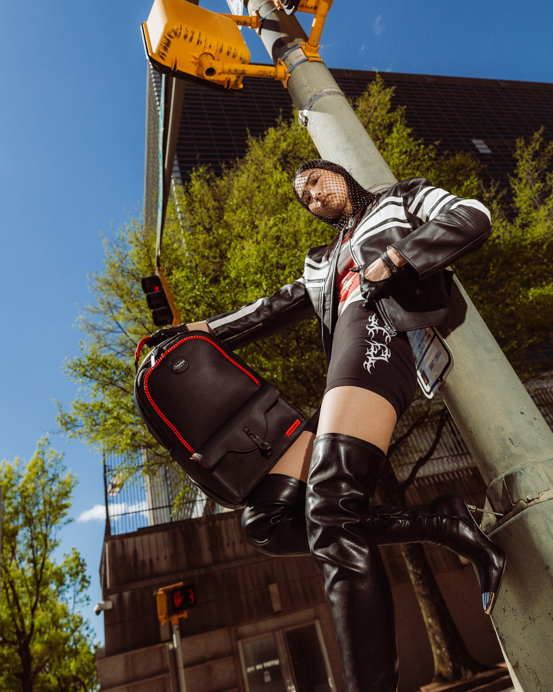 Front view of the faux leather backpack with cargo pocket and red chain embellishments