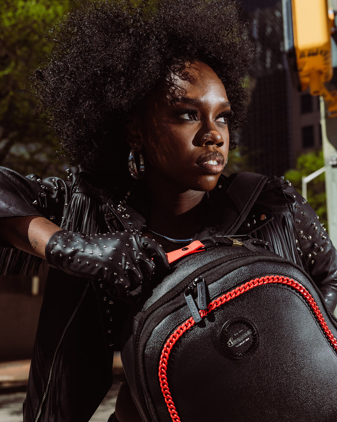 Front view of the faux leather backpack with cargo pocket and red chain embellishments