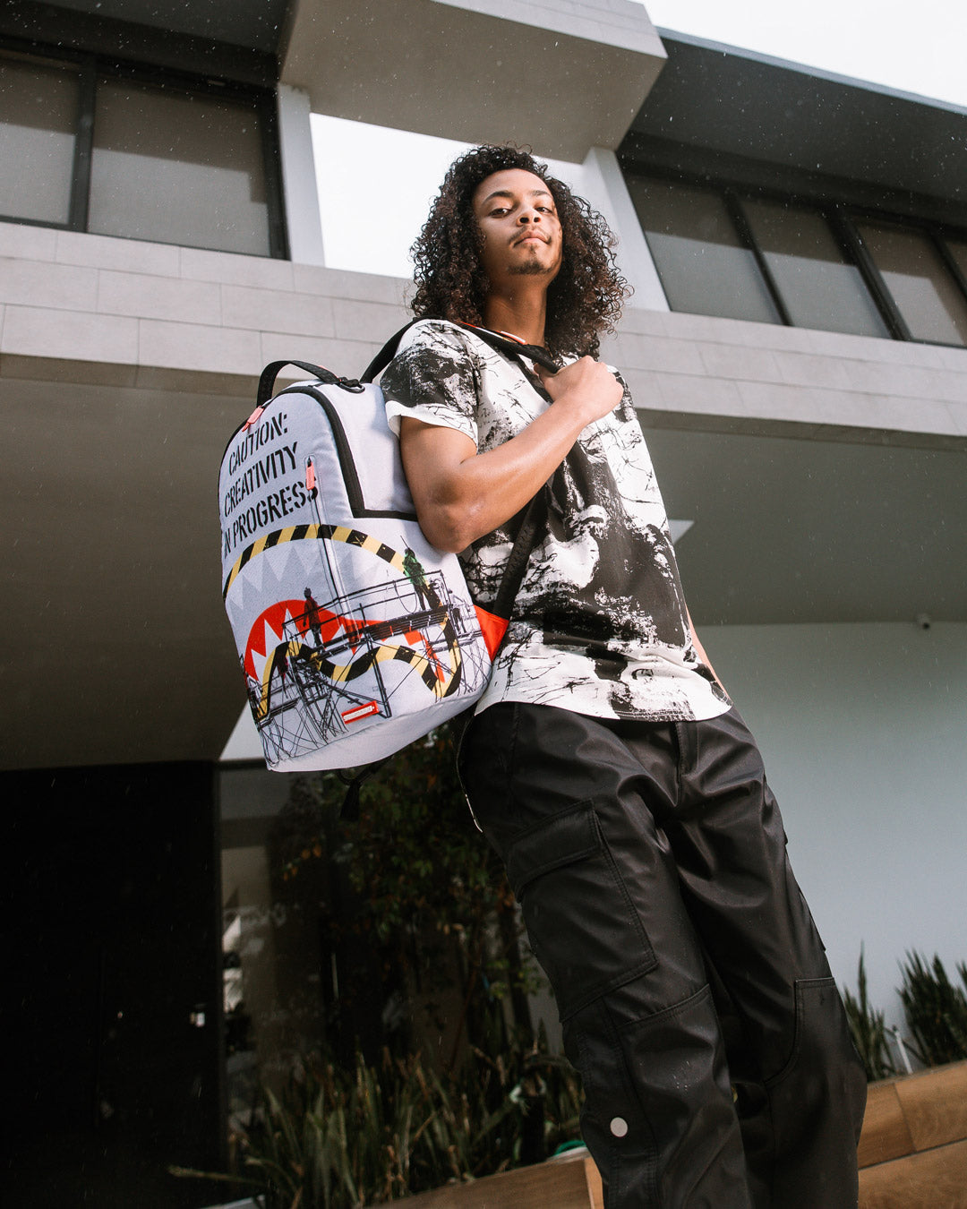 Front view of Sprayground Creativity Deluxe Backpack with gold zippers.