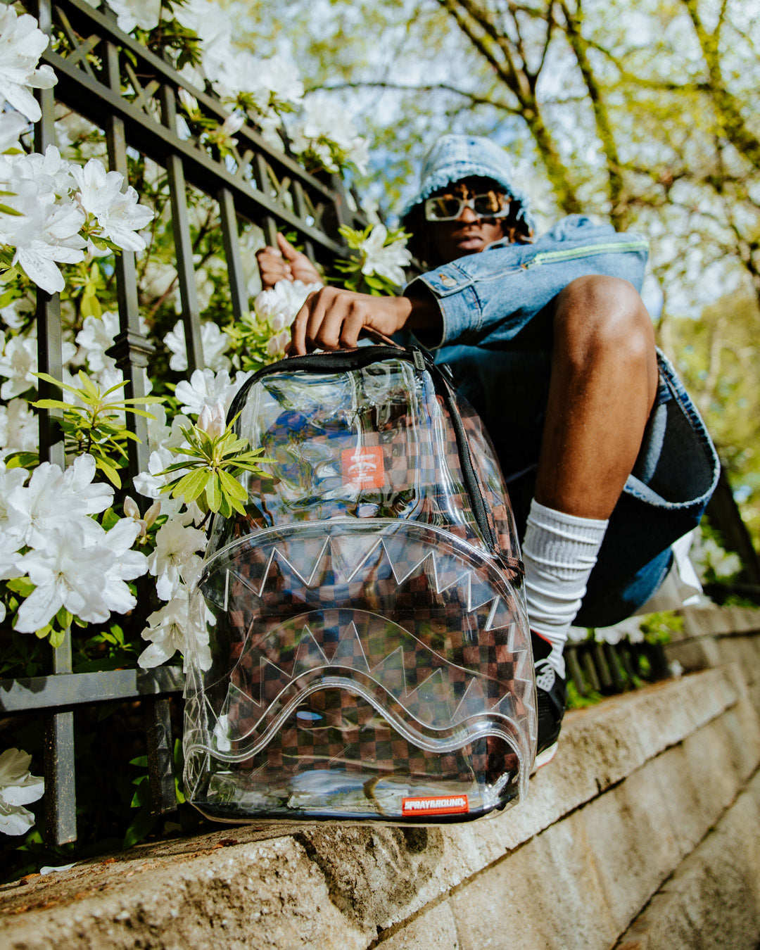 Clear DLX backpack front view, highlighting its clear vinyl fabric and front zipper pocket.