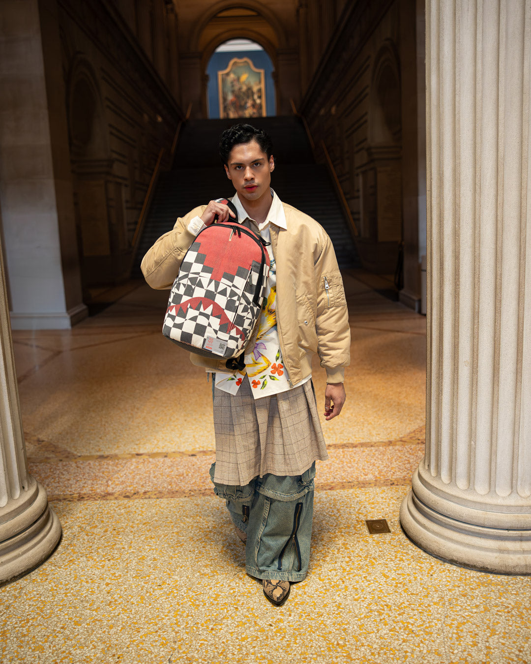 Front view of the Sprayground backpack showcasing the Inca checkerboard pattern and ruby-red details