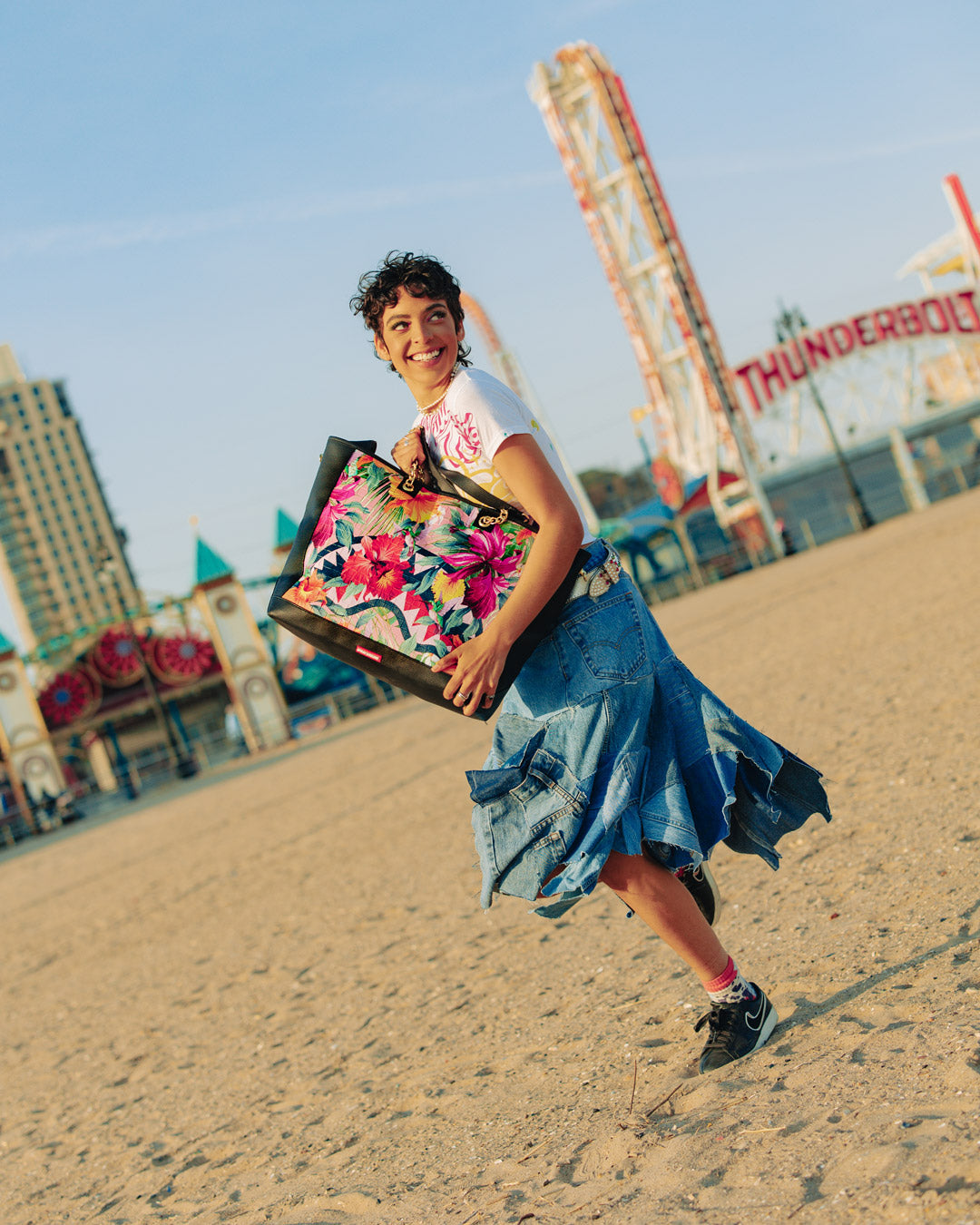 Front view of Sprayground shark-print faux leather tote bag on a city sidewalk