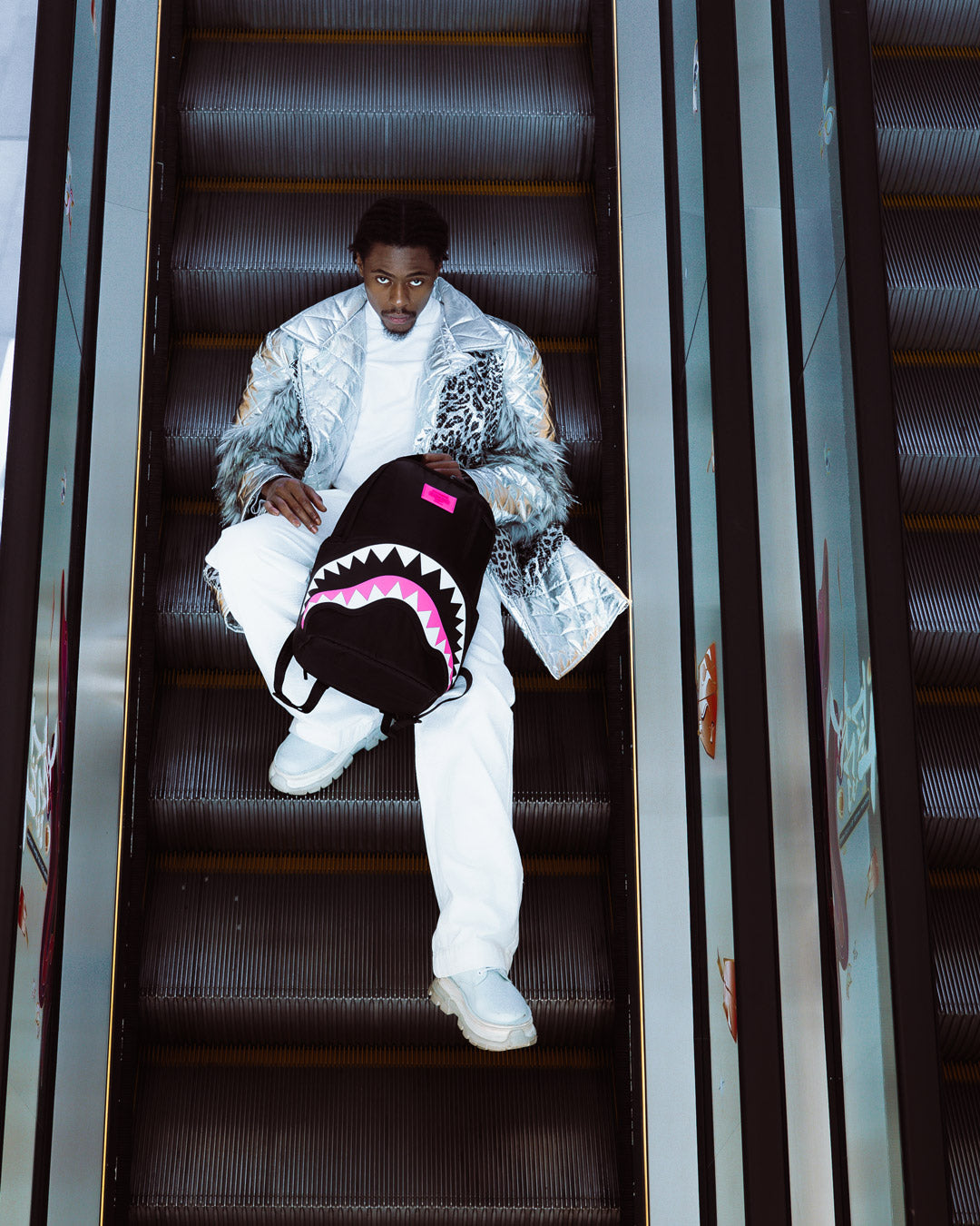 Sprayground Shark Mouth Neon Venom Backpack being used for travel, connected to a carry-on luggage