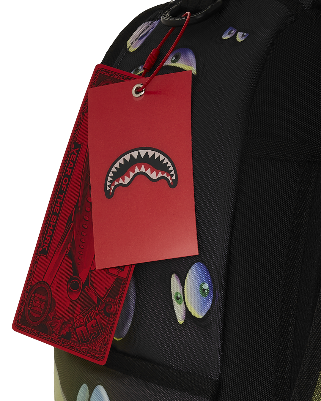 Close-up of gold zippers and Sprayground badge on designer backpack.