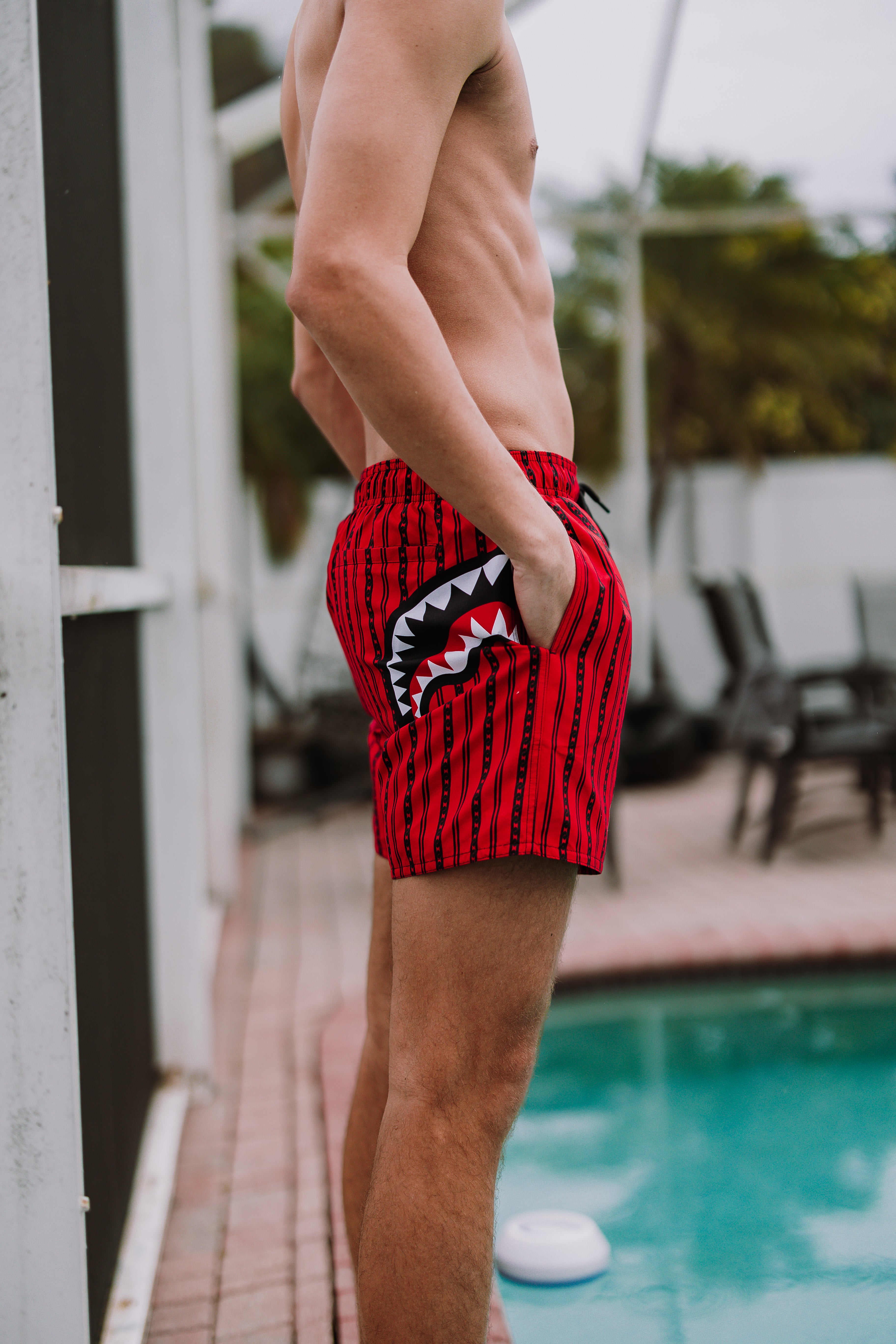 Model relaxing on coastal rocks wearing swim shorts on a sunny day