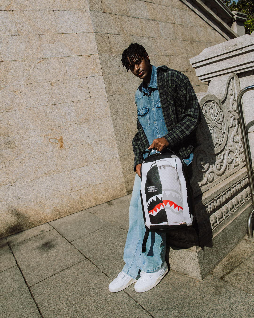 Model wearing Sprayground backpack with ergonomic straps in urban setting.