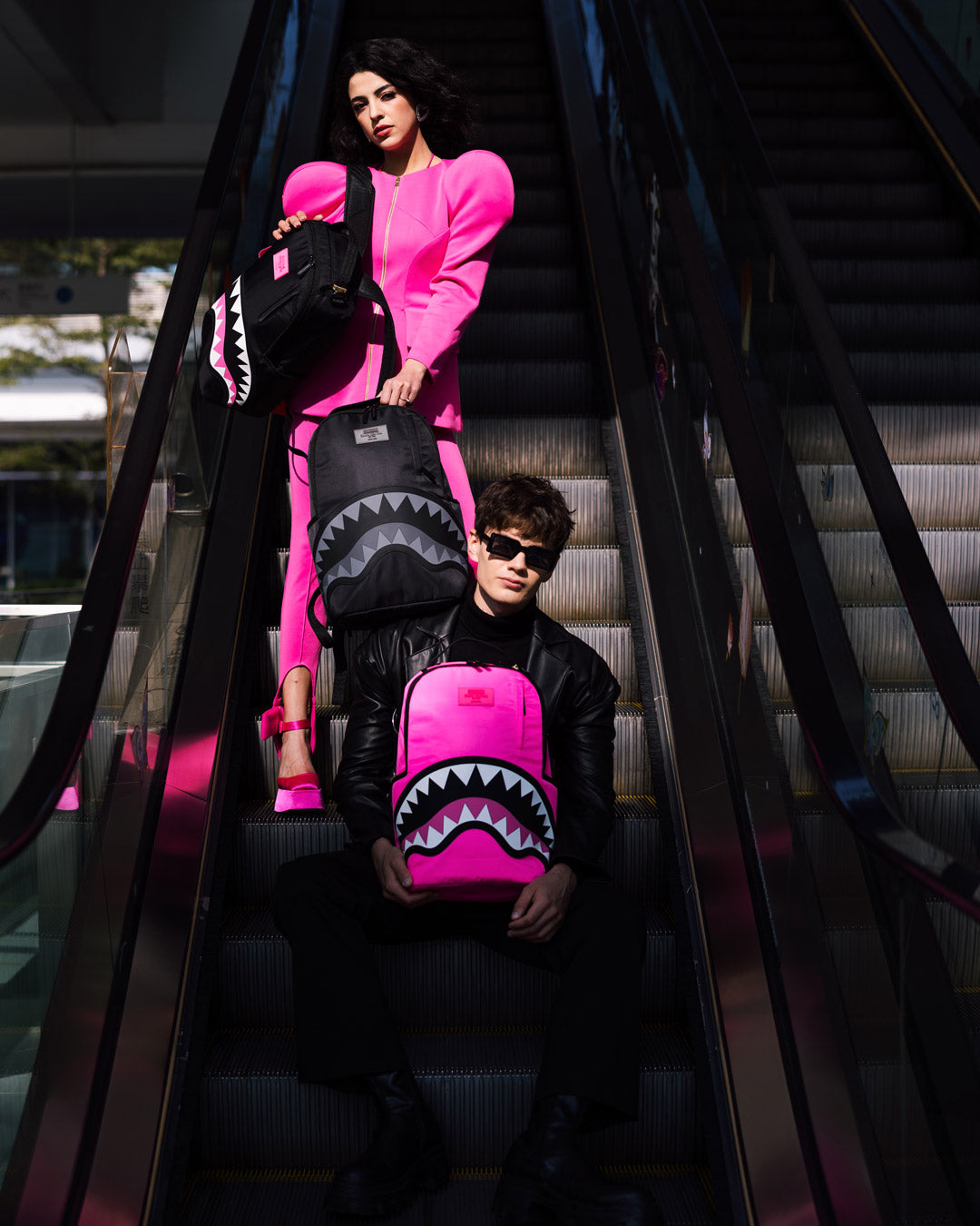 Sprayground Shark Mouth Neon Venom Backpack being used for travel, connected to a carry-on luggage