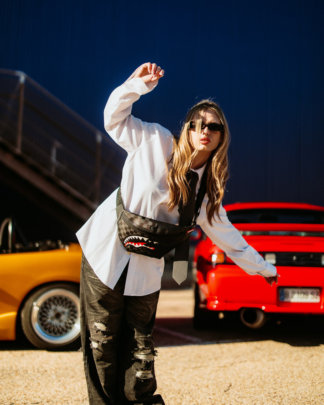 Close-up of the black leather crossbody bag showing zippered pocket and adjustable strap