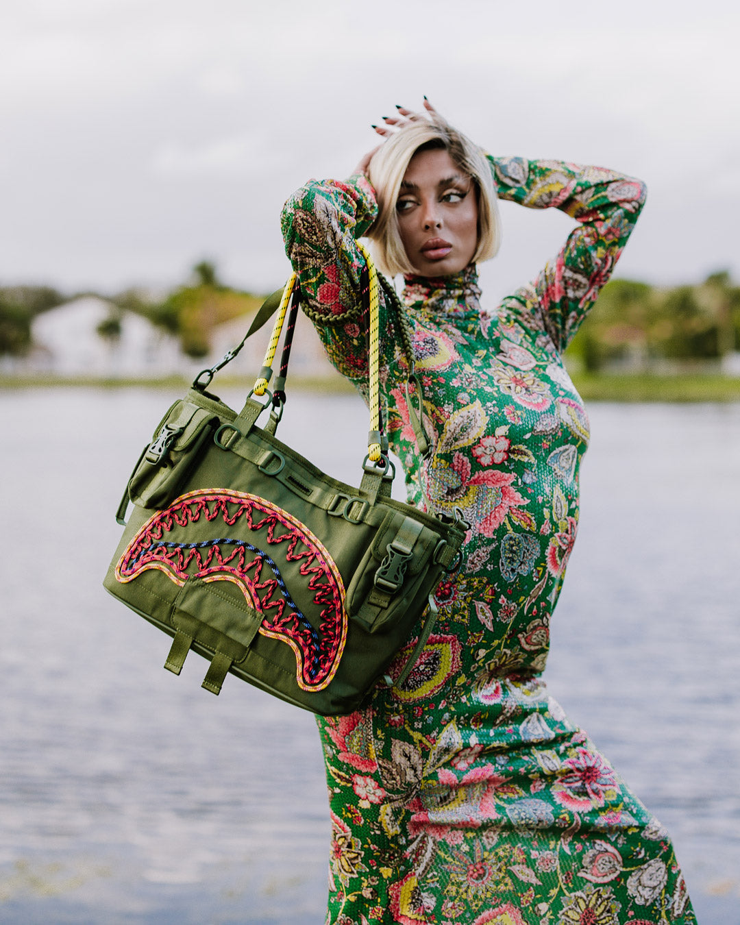 Sprayground leopard print tote bag held over shoulder, showcasing front pockets