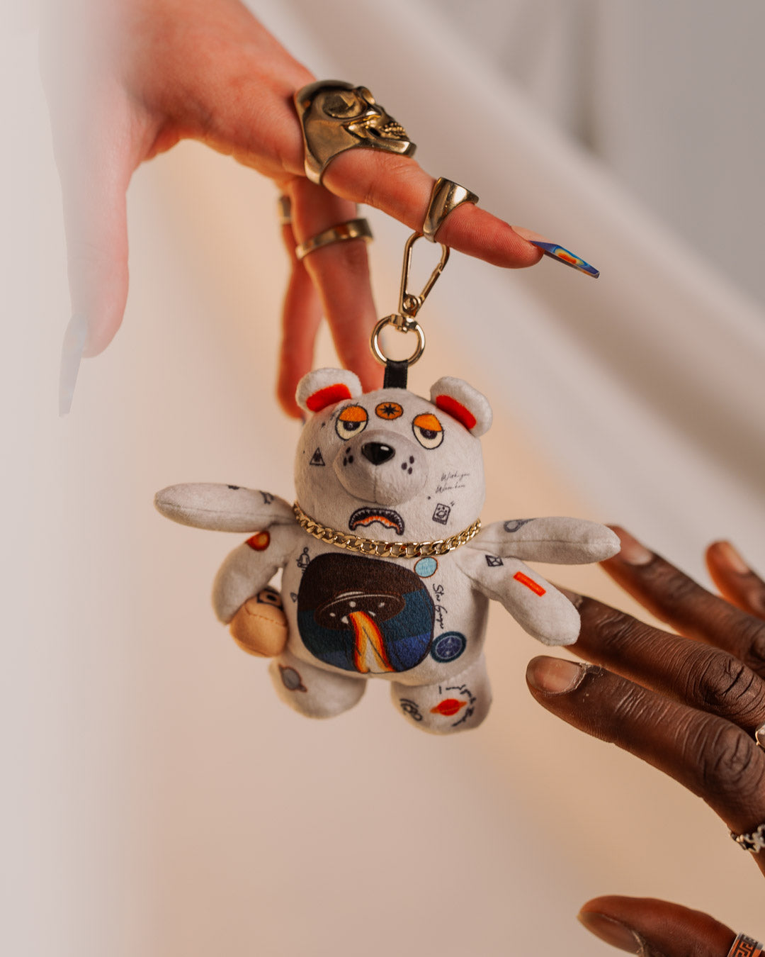 Close-up of a plush bear keychain with gold chain hanging from a backpack