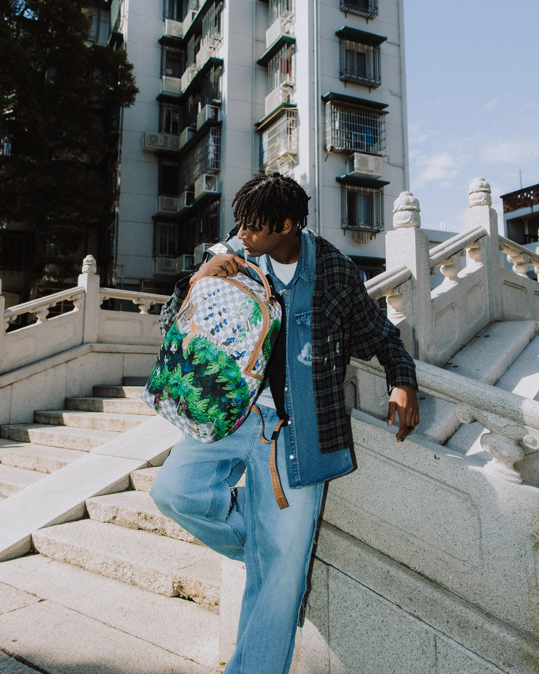 Front angle of pink Sprayground backpack with shark mouth design on city pavement