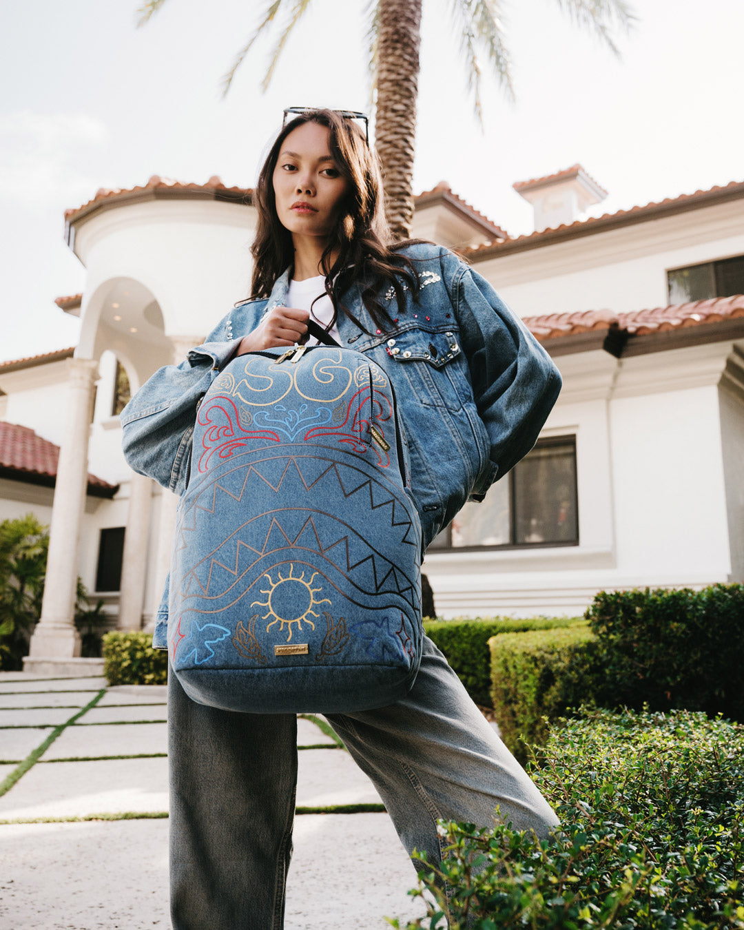 Front view showing gold zippers and denim texture on designer backpack