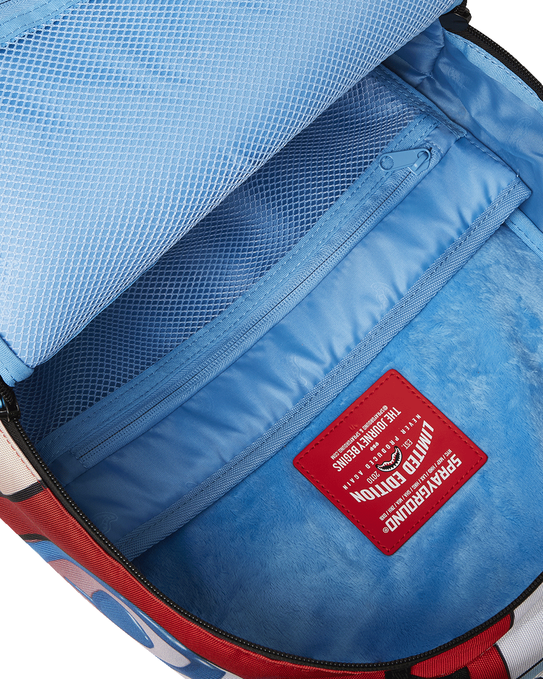 Close-up of gold zippers and Sprayground badge on the artist-style backpack.