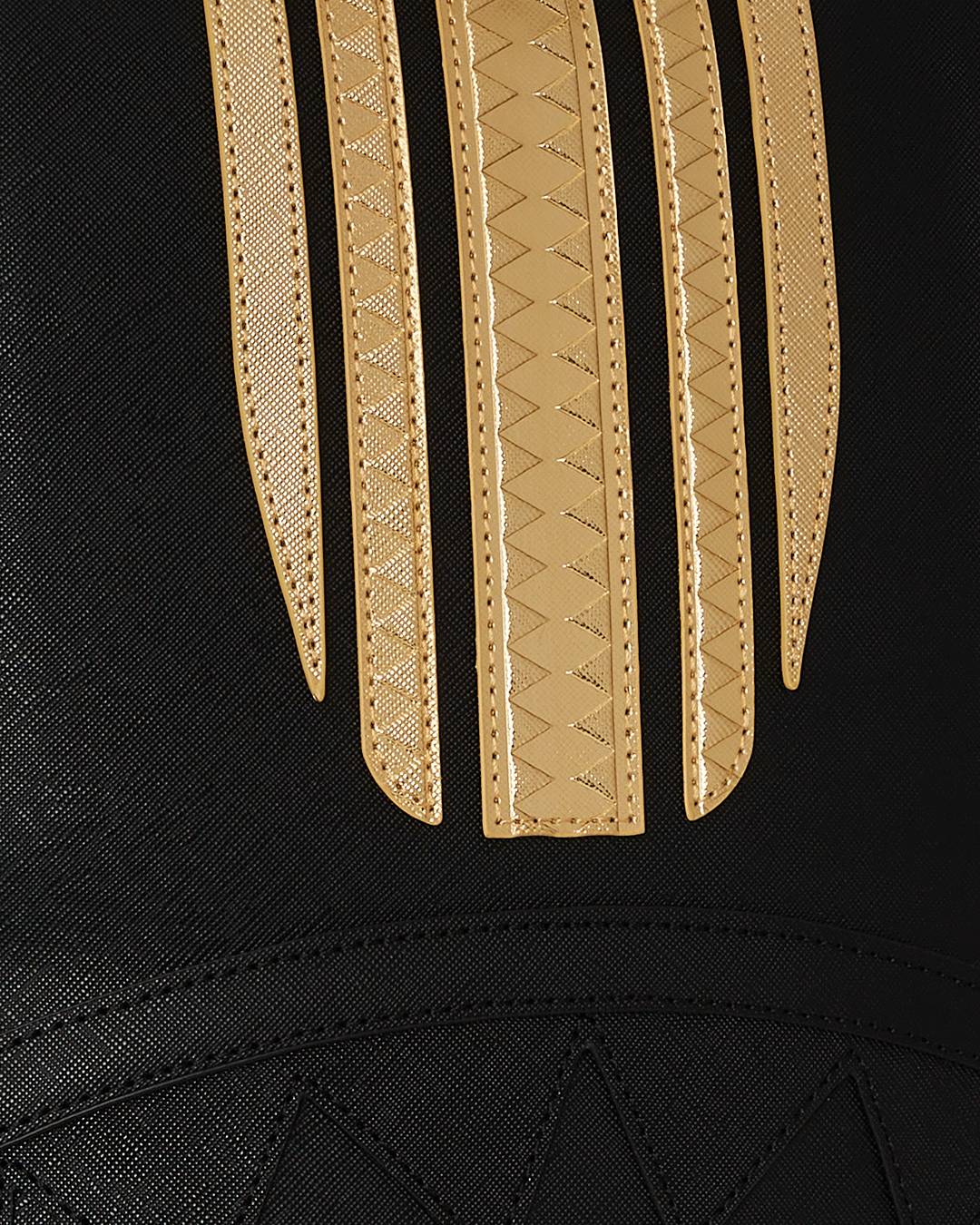 Close-up of the gold zipper and metal Sprayground Authentic badge on the backpack.