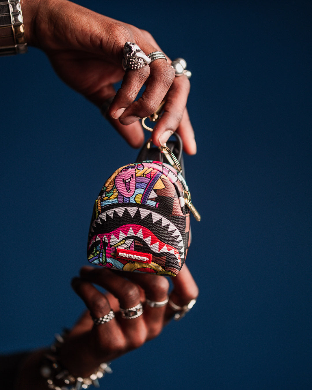 Mini backpack keychain attached to a backpack, showcasing its compact size.