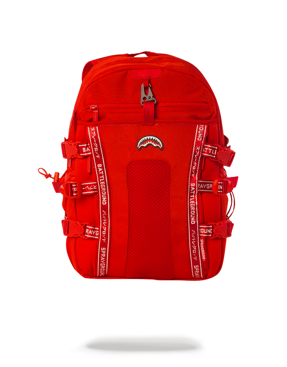 Nomad Red backpack worn by a woman at an airport, showing side pockets and adjustable straps