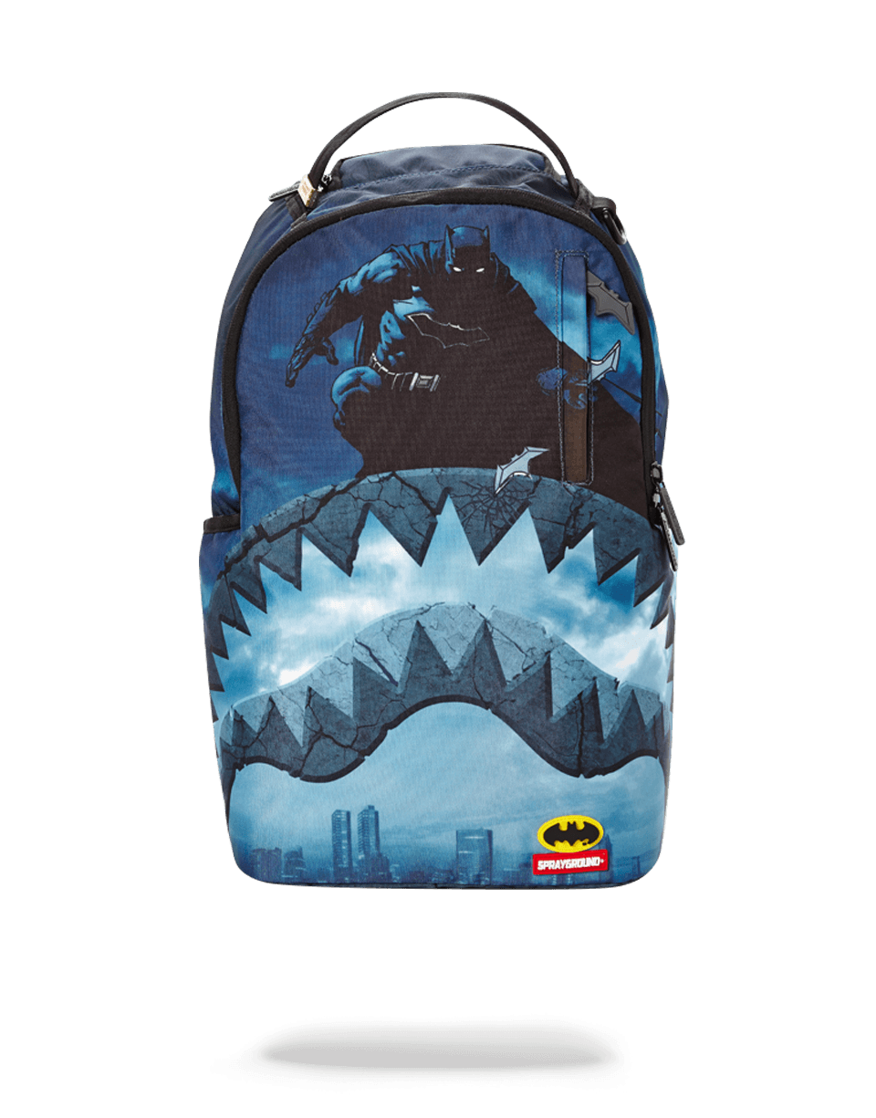 Front view of Sprayground shark backpack with Batman design in urban setting.