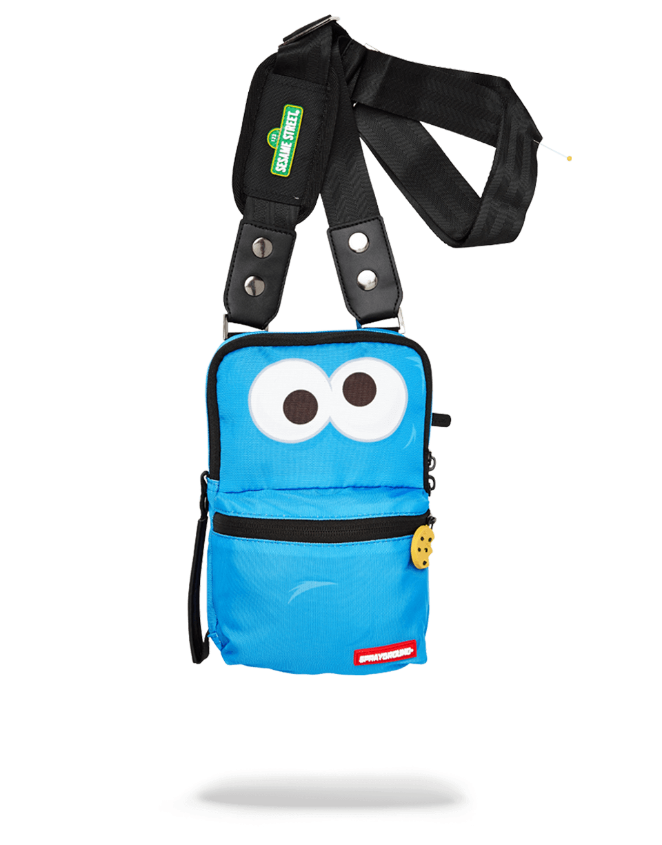Front view of Sprayground Cookie Monster crossbody bag on a city street.